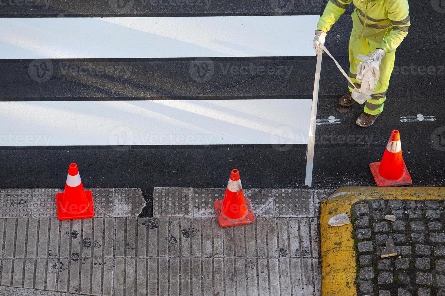 Worker removing masking tape after painting a zebra crossing on a city road photo