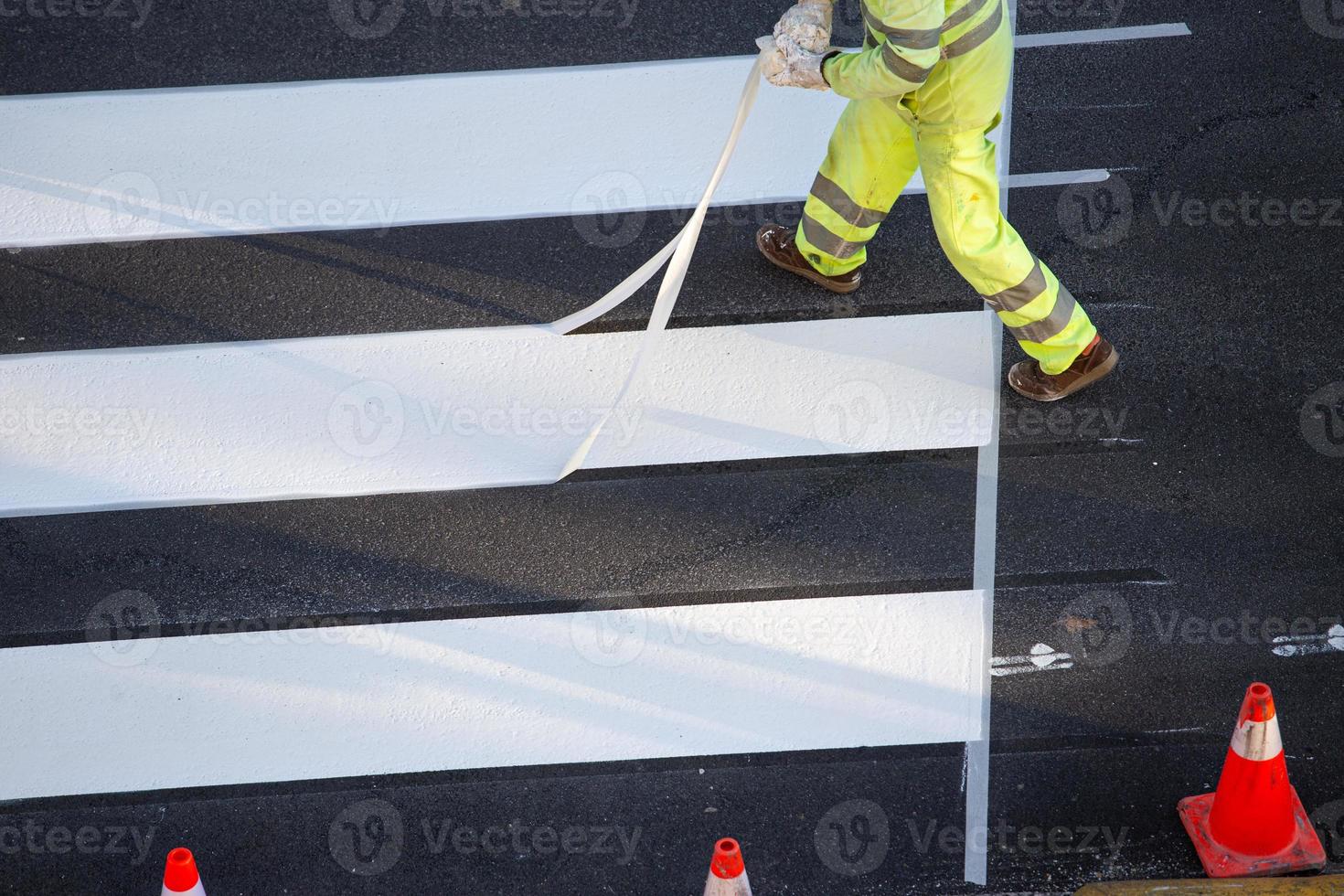 Worker removing masking tape after painting a zebra crossing on a city road photo