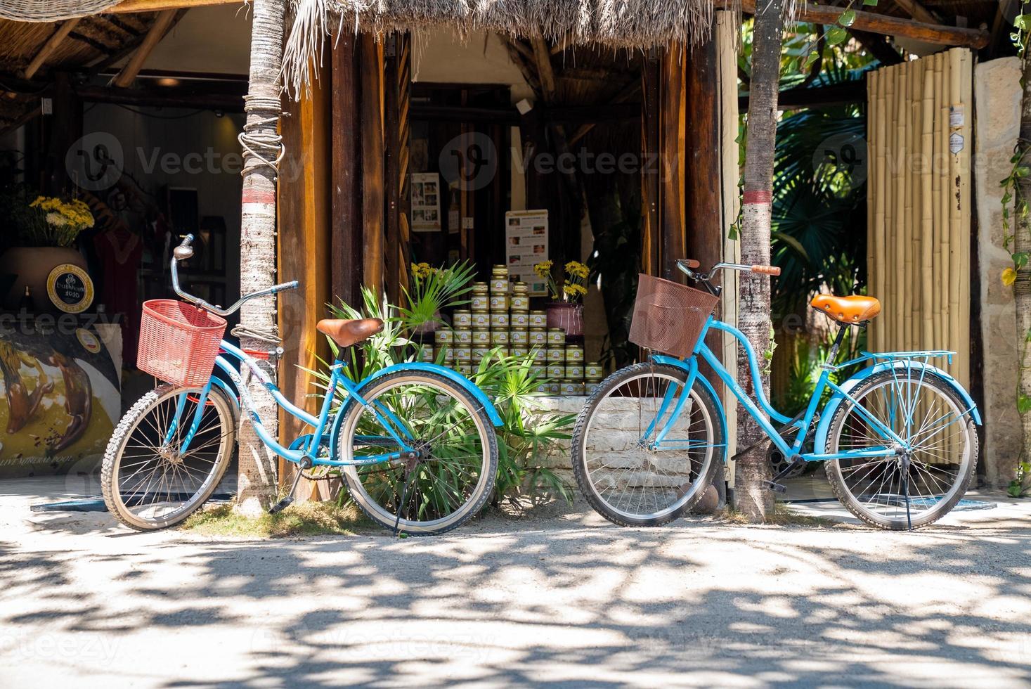 Two bicycles parked at roadside storefront with stack of jars photo