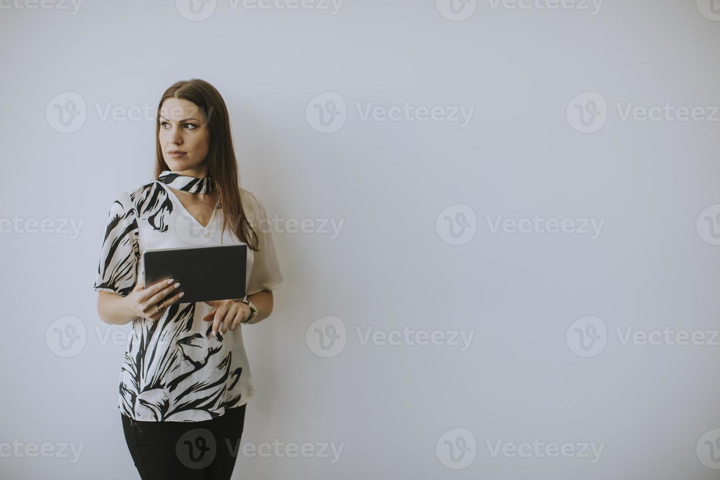 Business woman using digital tablet by the wall in the office photo