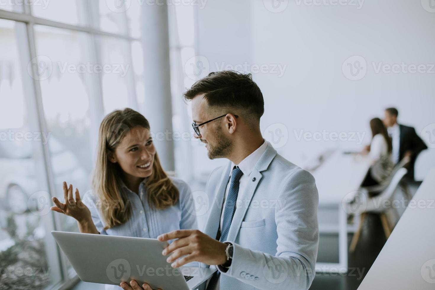 Pareja de jóvenes empresarios trabajando y discutiendo por ordenador portátil en la oficina foto