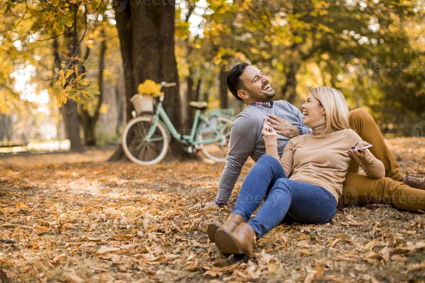 Young couple sitting on ground in autumn park photo