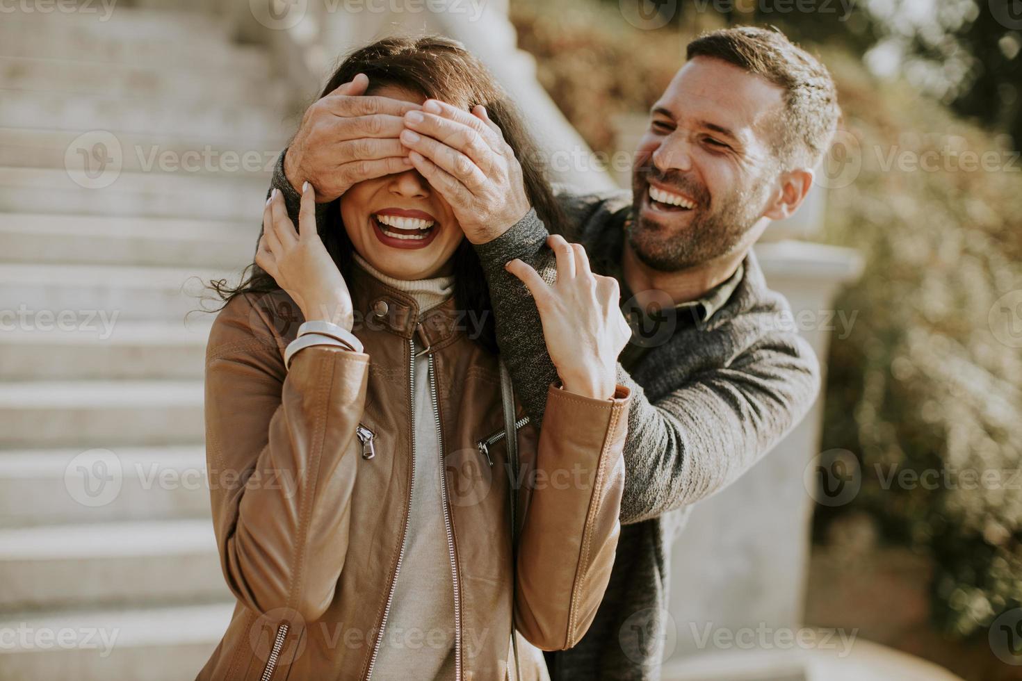 joven que cubre los ojos de su novia en el parque foto