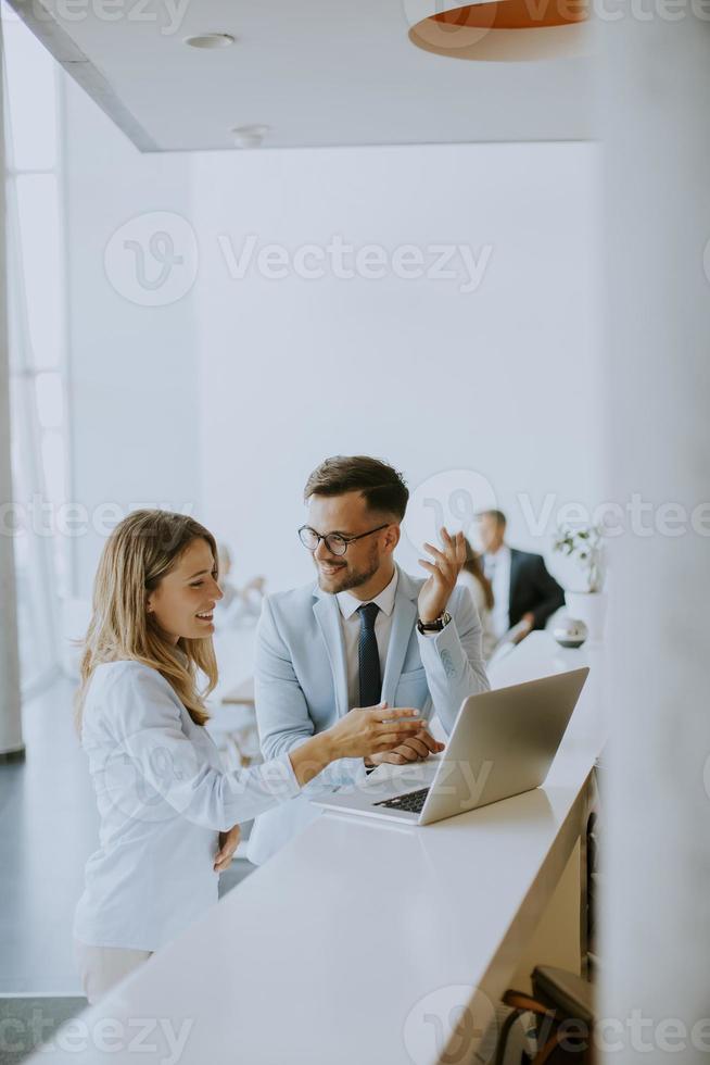 Pareja de jóvenes empresarios trabajando y discutiendo por ordenador portátil en la oficina foto