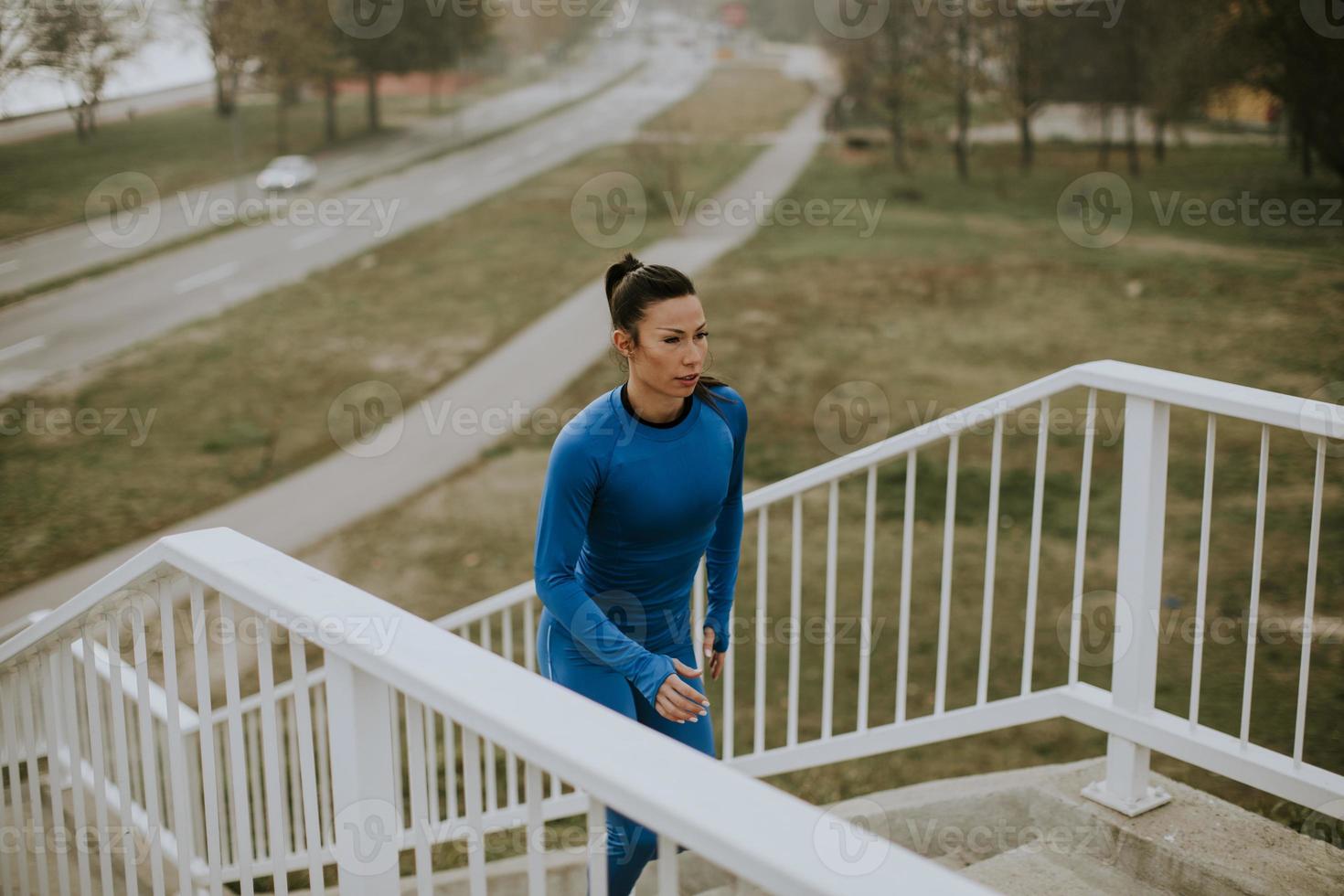 Mujer joven en traje azul corriendo en las escaleras al aire libre en la mañana de otoño foto