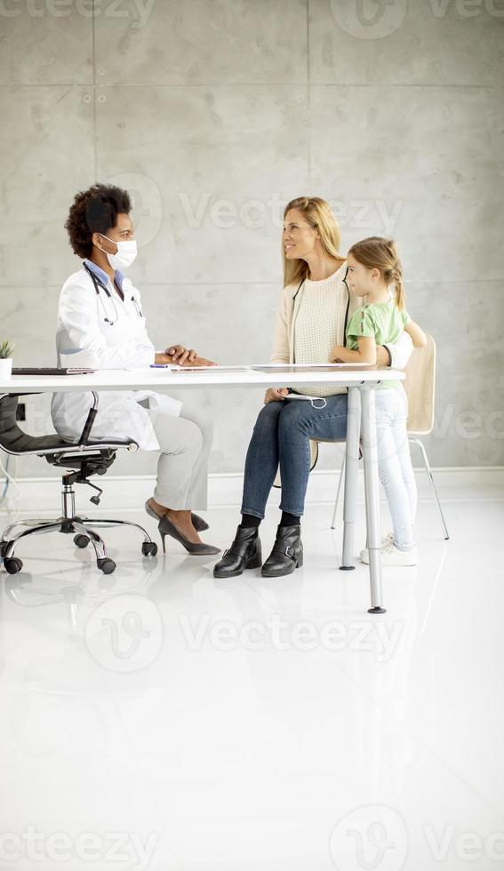 niña linda con su madre en el examen del pediatra foto