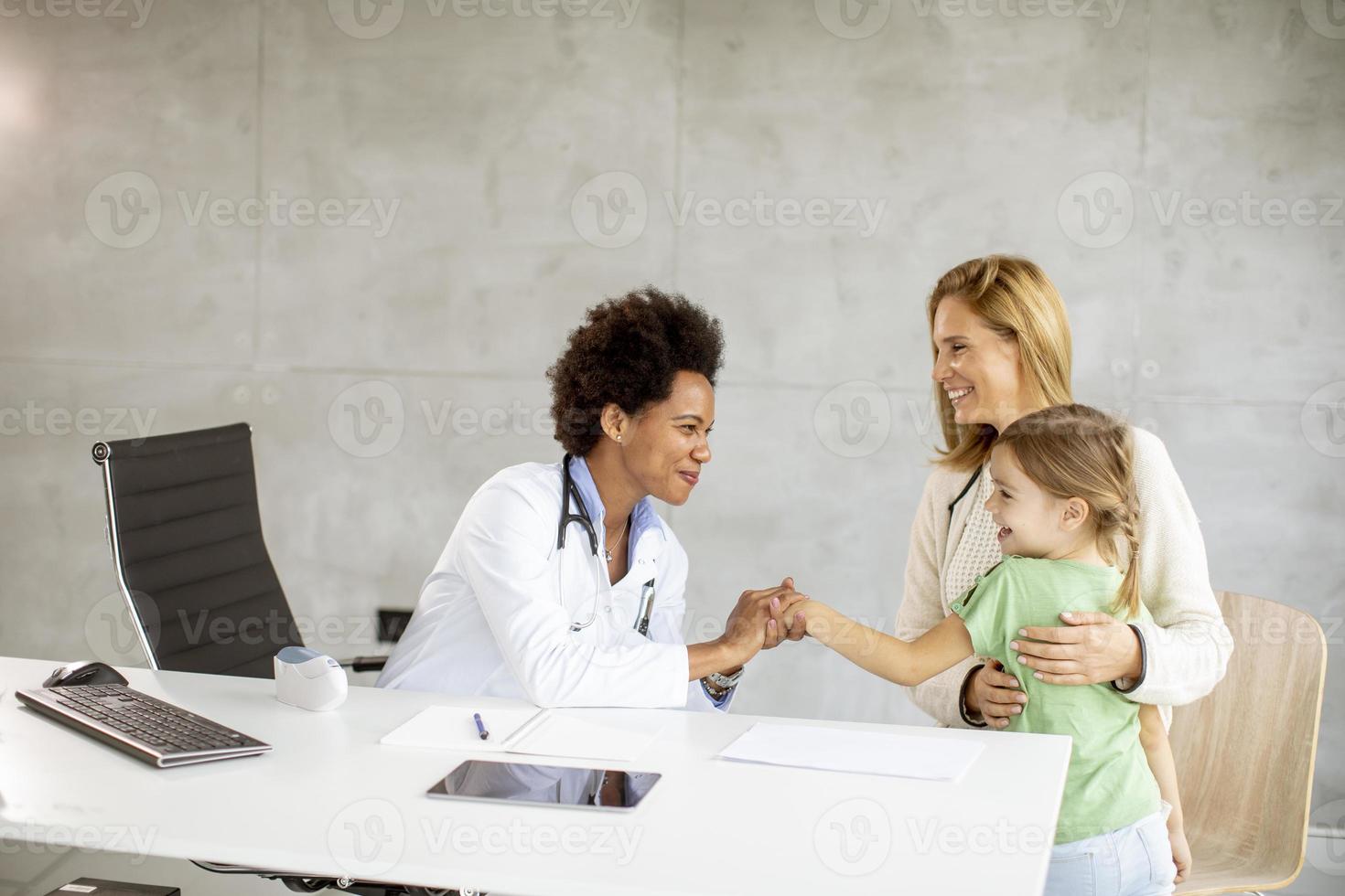 niña linda con su madre en el examen del pediatra foto