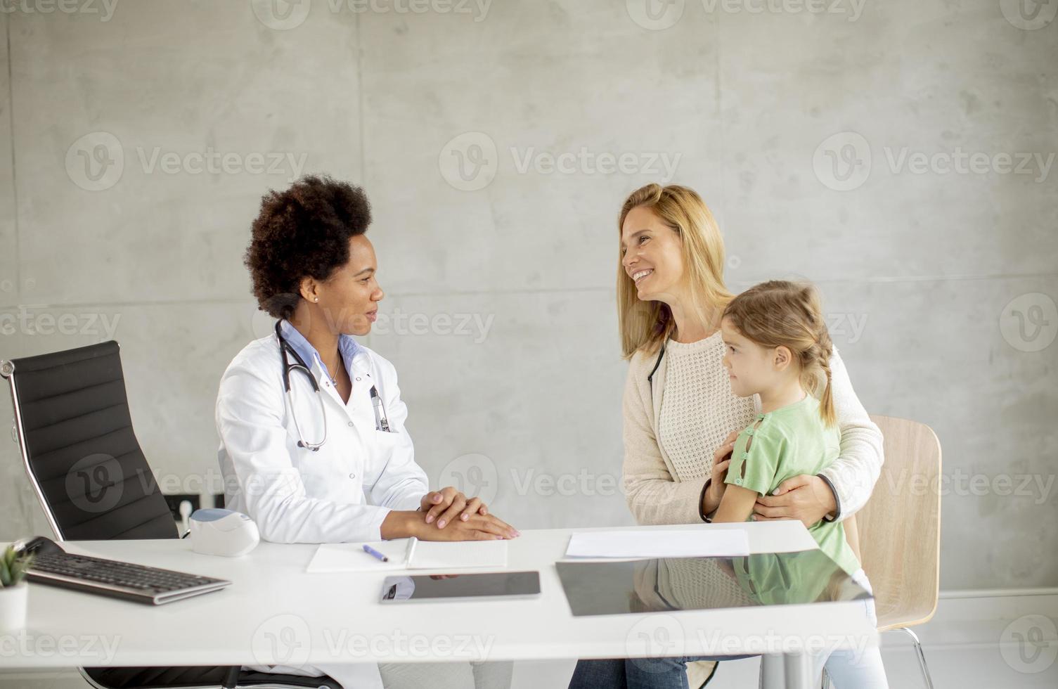 niña linda con su madre en el examen del pediatra foto