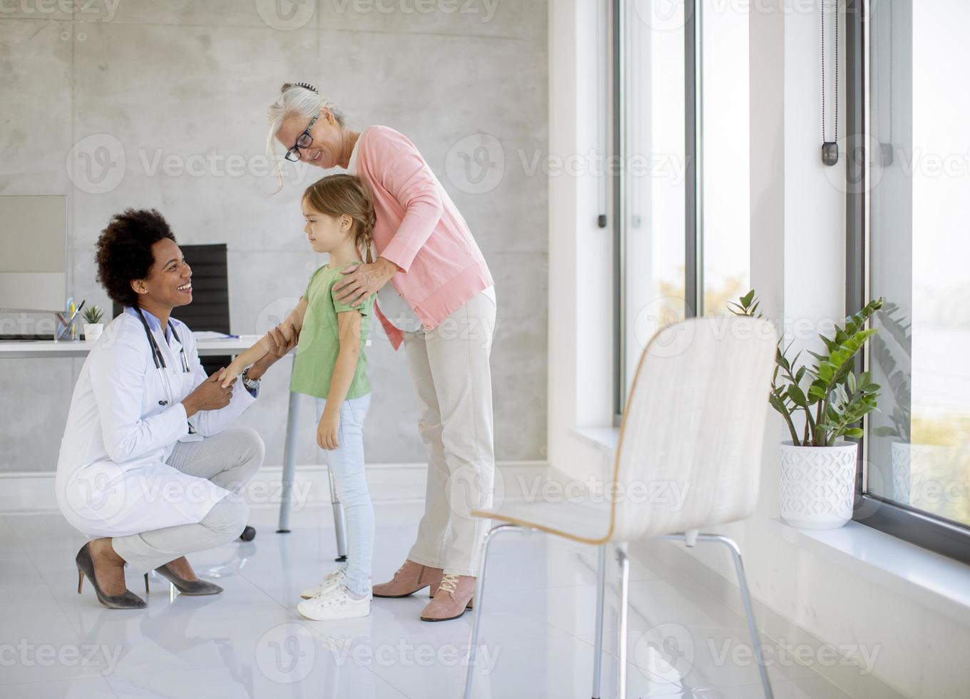 Cute little girl with her grandmother at the pediatrician examination photo