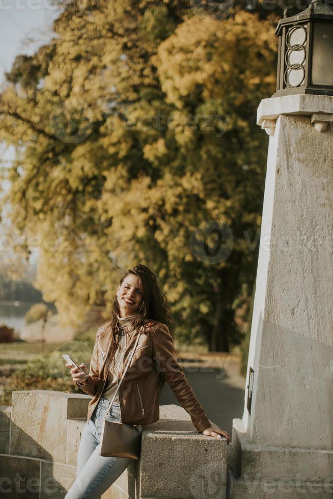 Mujer joven con teléfono móvil en el parque en un día soleado de otoño foto