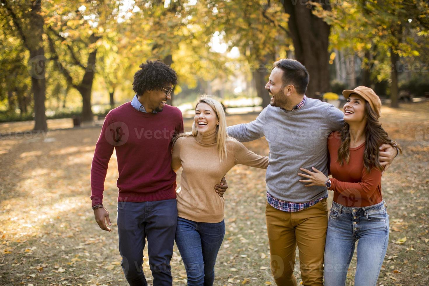 jóvenes multirraciales caminando en el parque de otoño foto