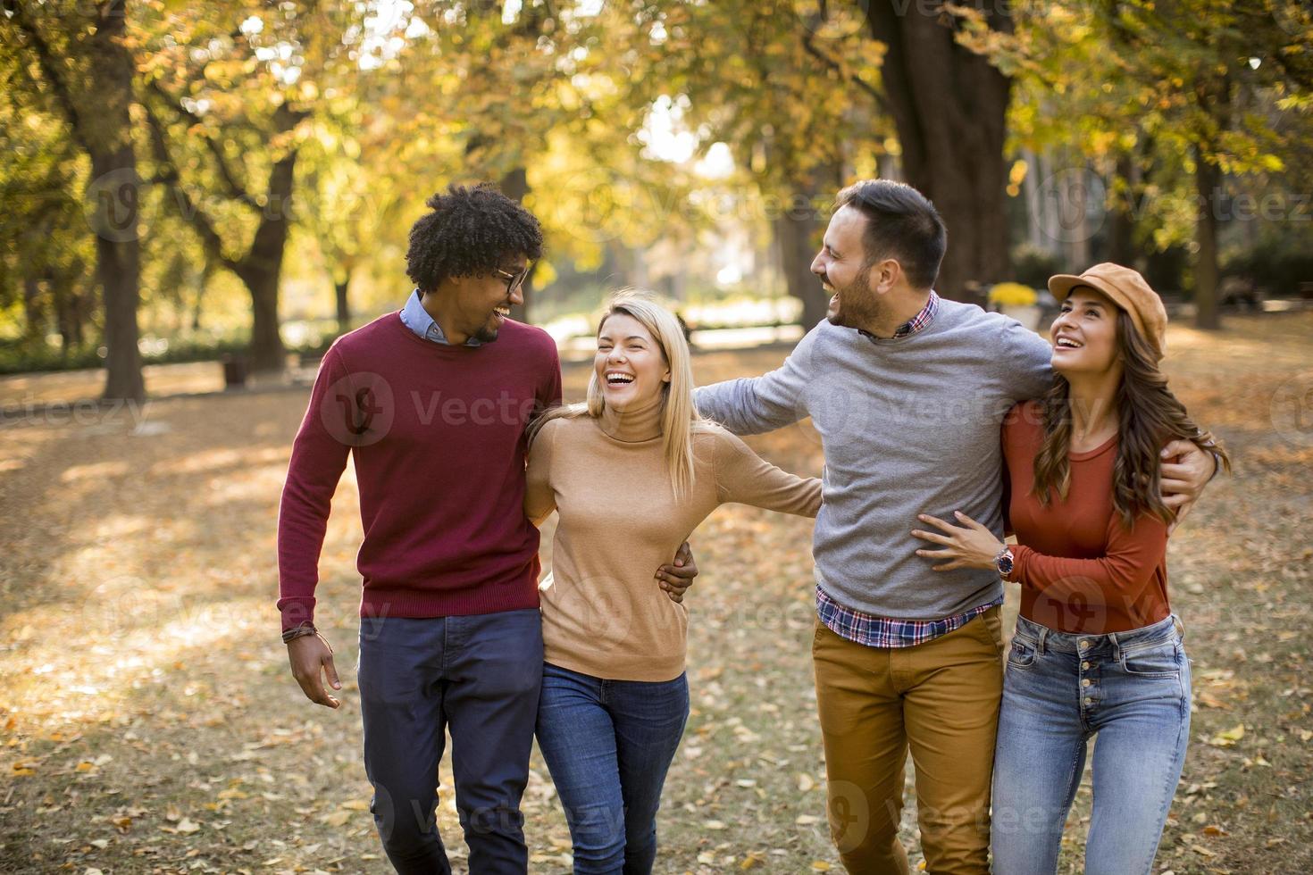 jóvenes multirraciales caminando en el parque de otoño foto