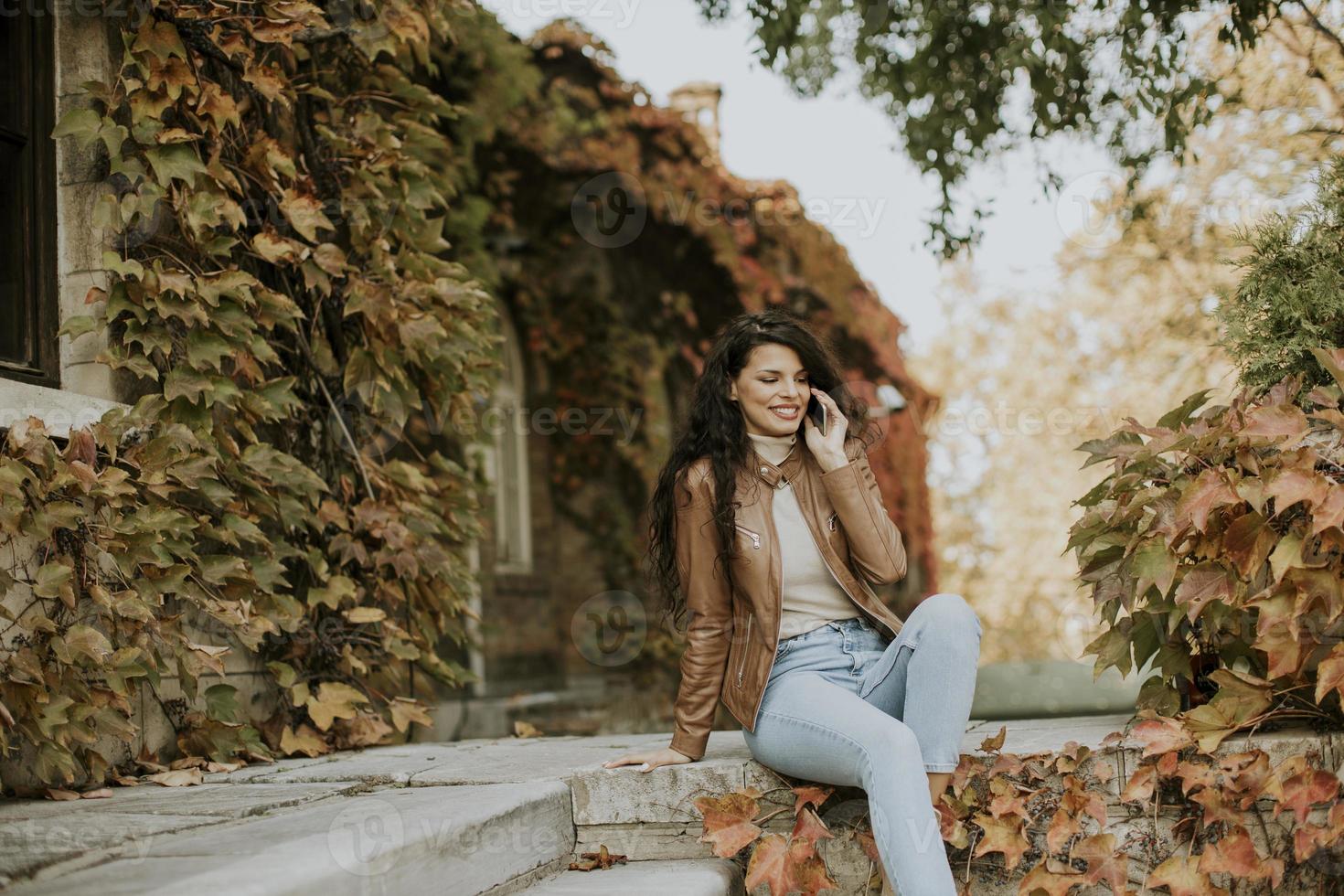 Young woman with mobile phone on autumn day photo