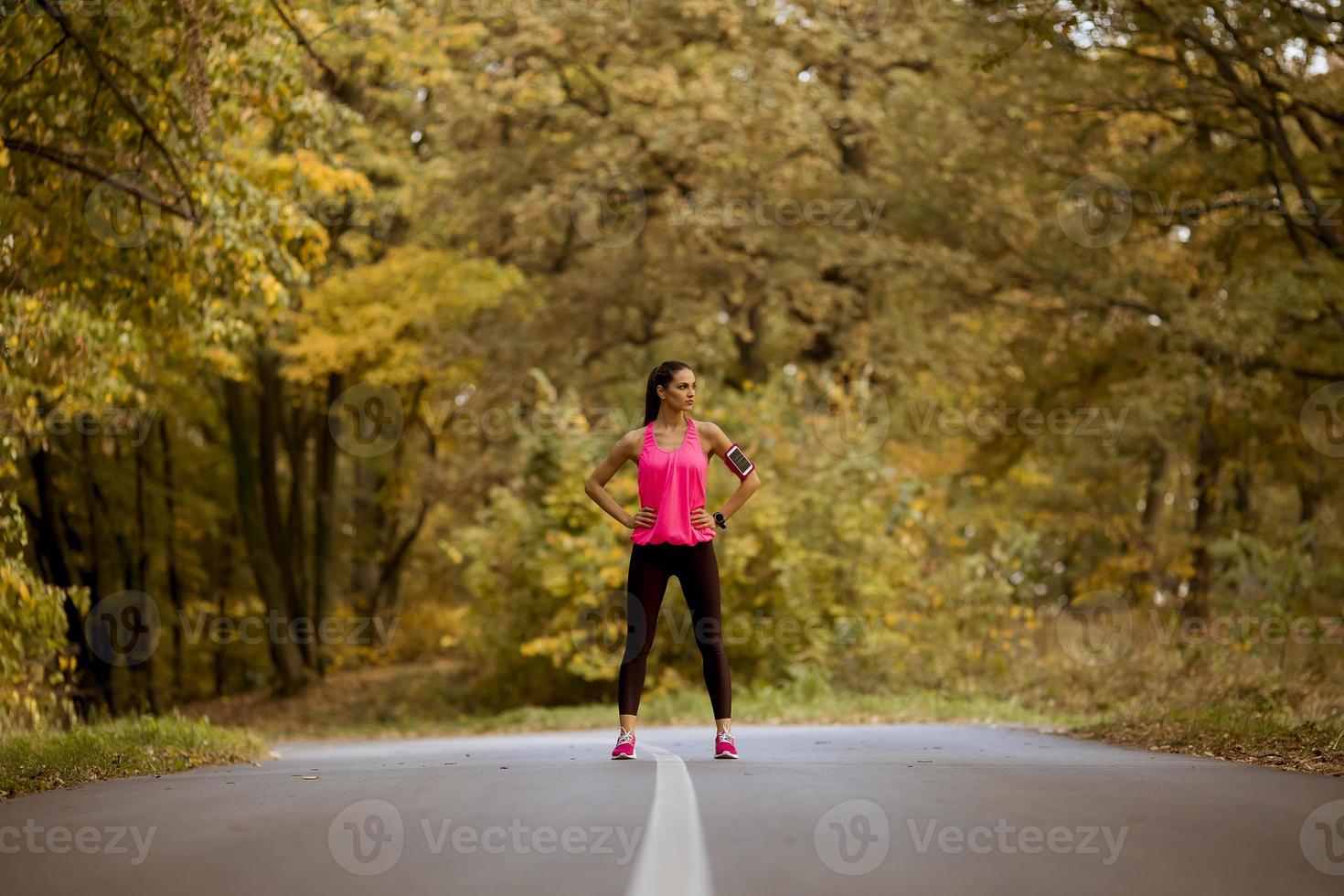 Mujer joven tiene un descanso durante el entrenamiento en el bosque de otoño foto