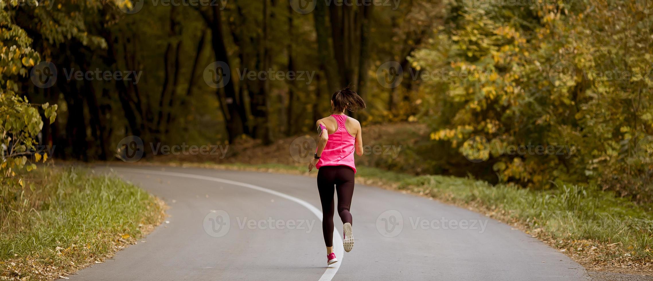 Young fitness woman running at forest trail photo