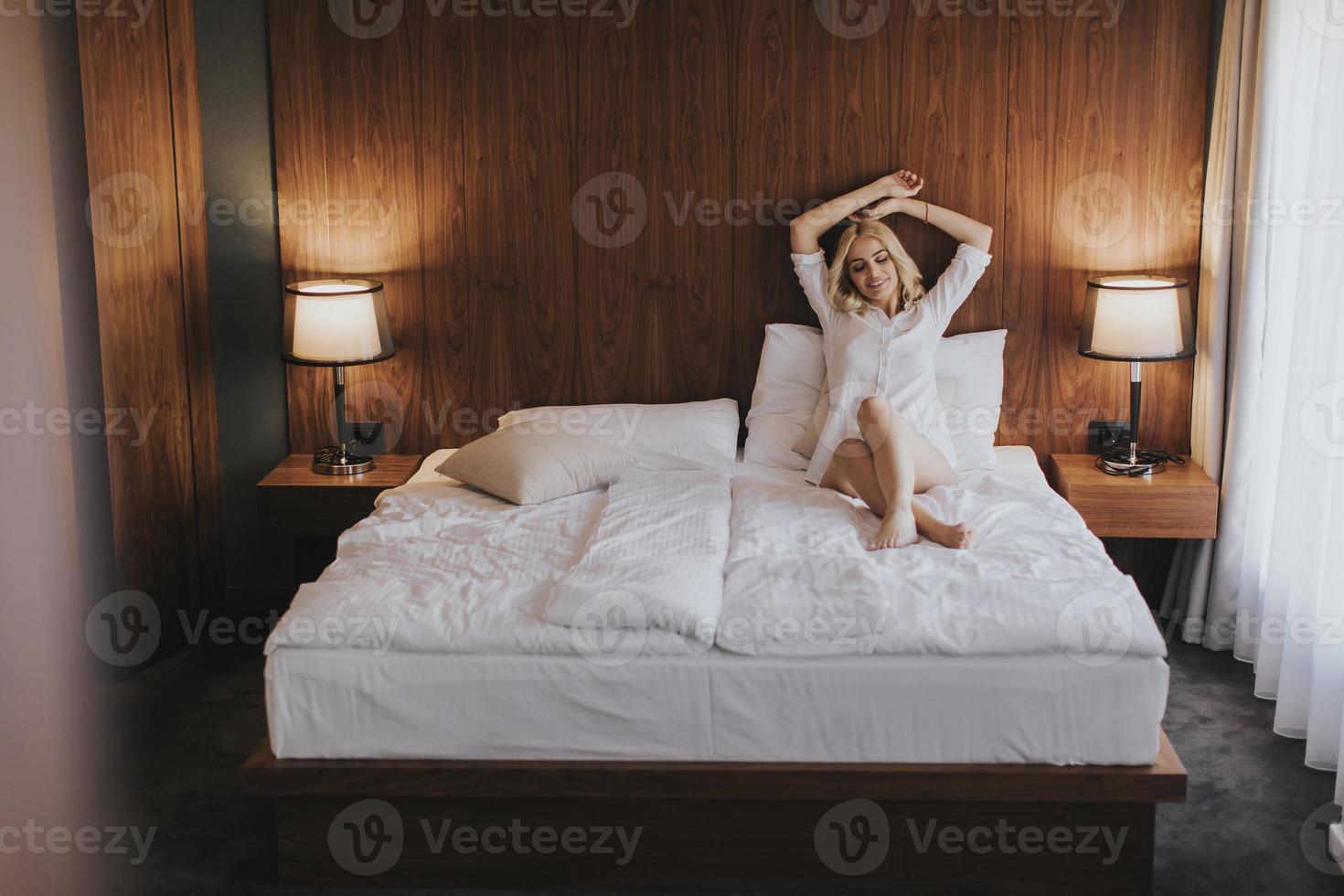 Young woman sitting on the bed at room photo