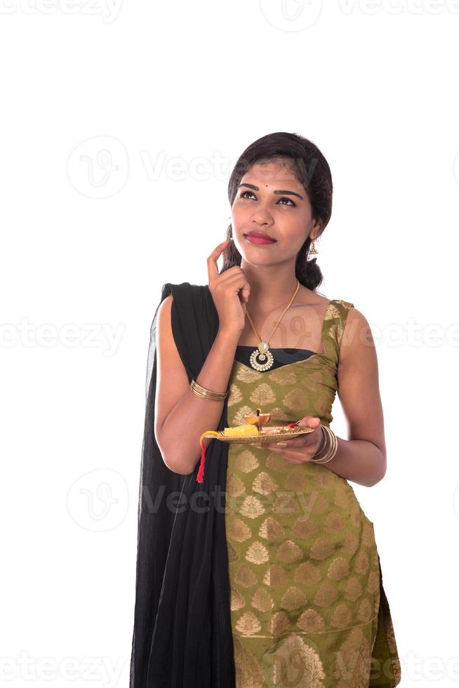 Indian Girl performing worship, portrait of a beautiful young lady with pooja thali isolated on white background. photo