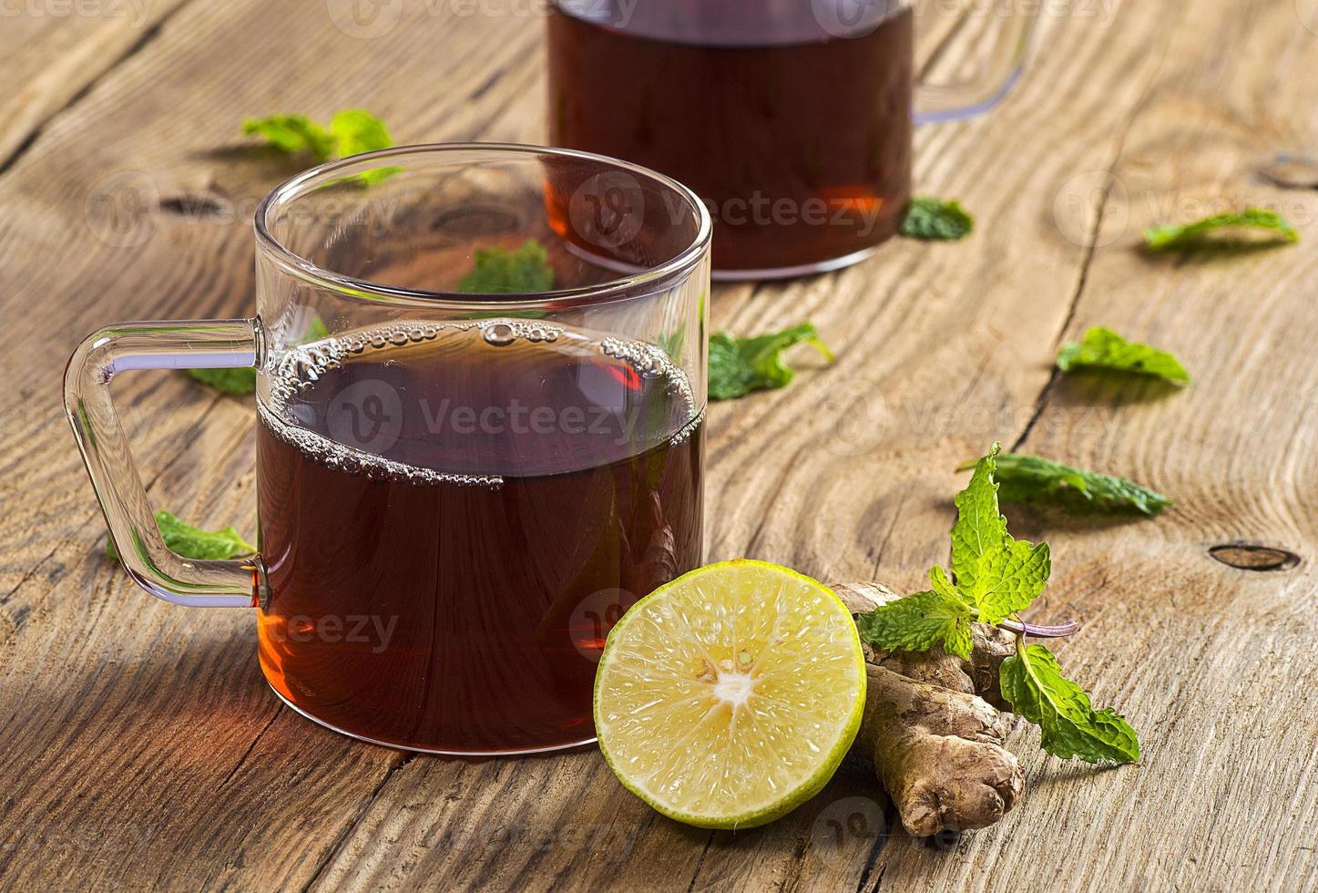 Cup of tea with ginger, lemon and mint on wooden table photo