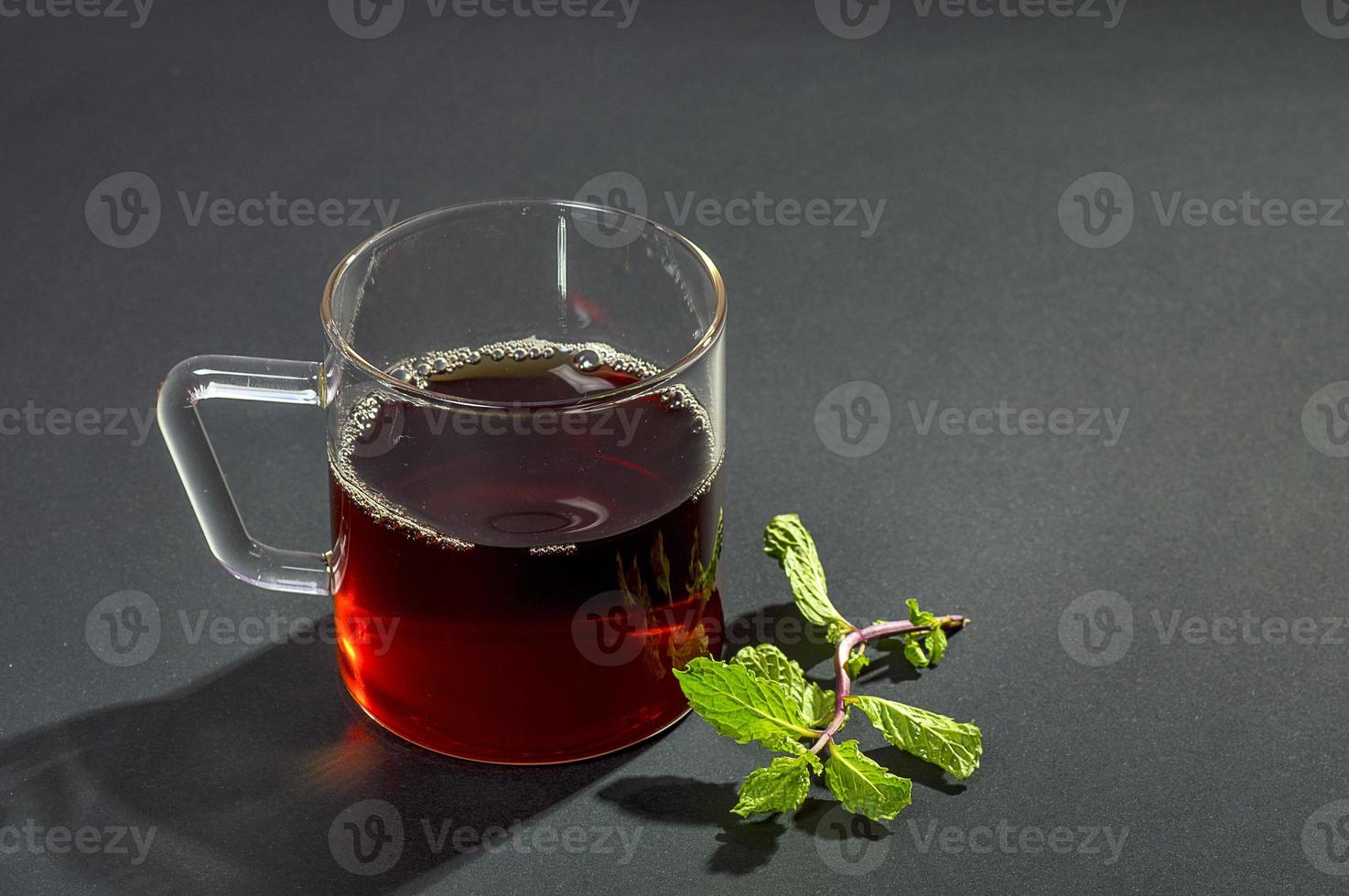 taza de té, menta y limón sobre fondo oscuro foto