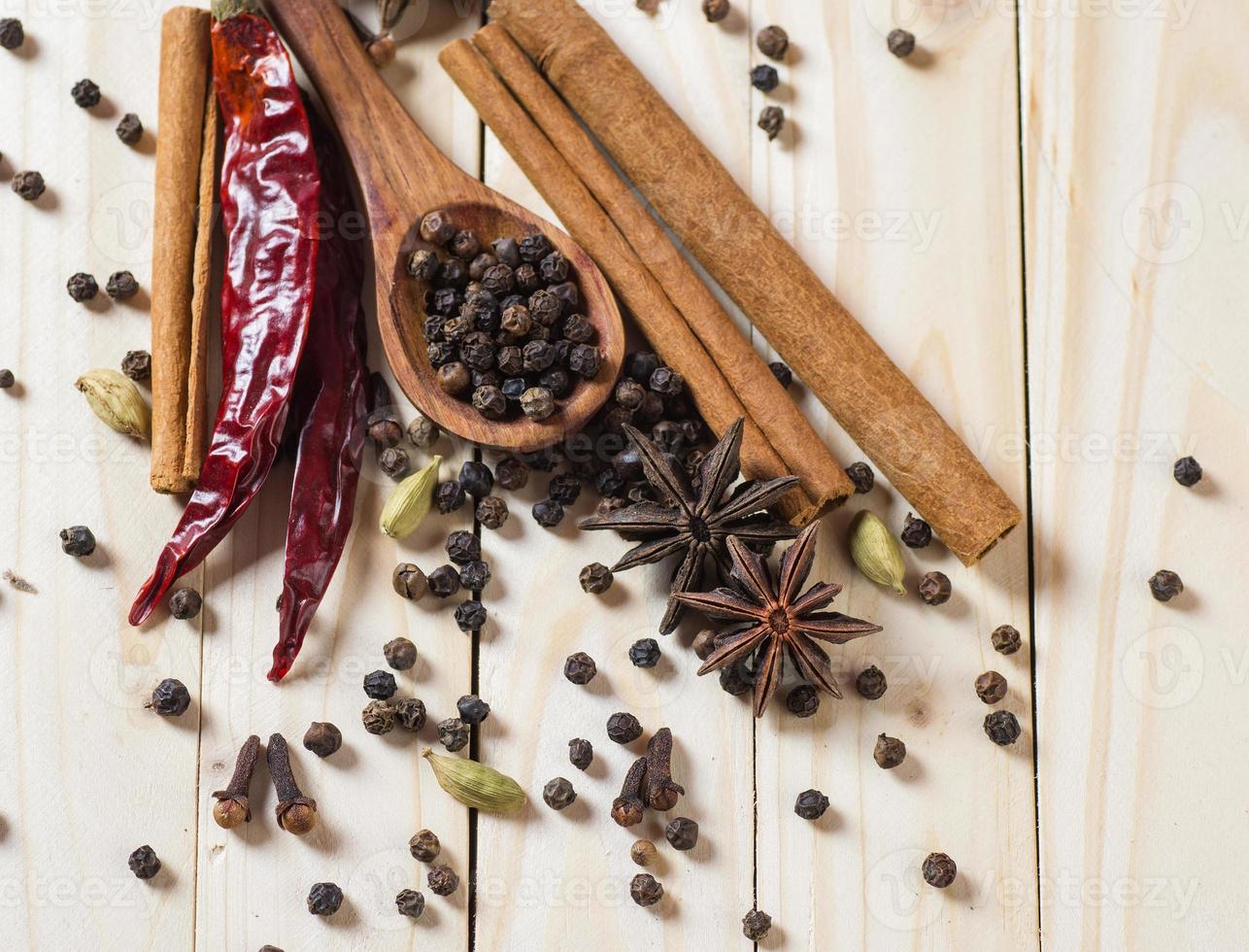 especias y hierbas. ingredientes de la comida y la cocina. Palitos de canela, estrellas de anís, pimienta negra, ají, cardamomo y clavo sobre un fondo de madera foto