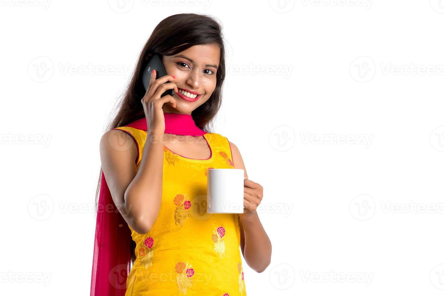 Pretty young girl calling on smartphone device while drinking tasty coffee or tea beverage photo