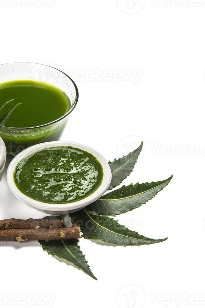 Medicinal Neem leaves in mortar and pestle with neem paste, juice and twigs on white background photo