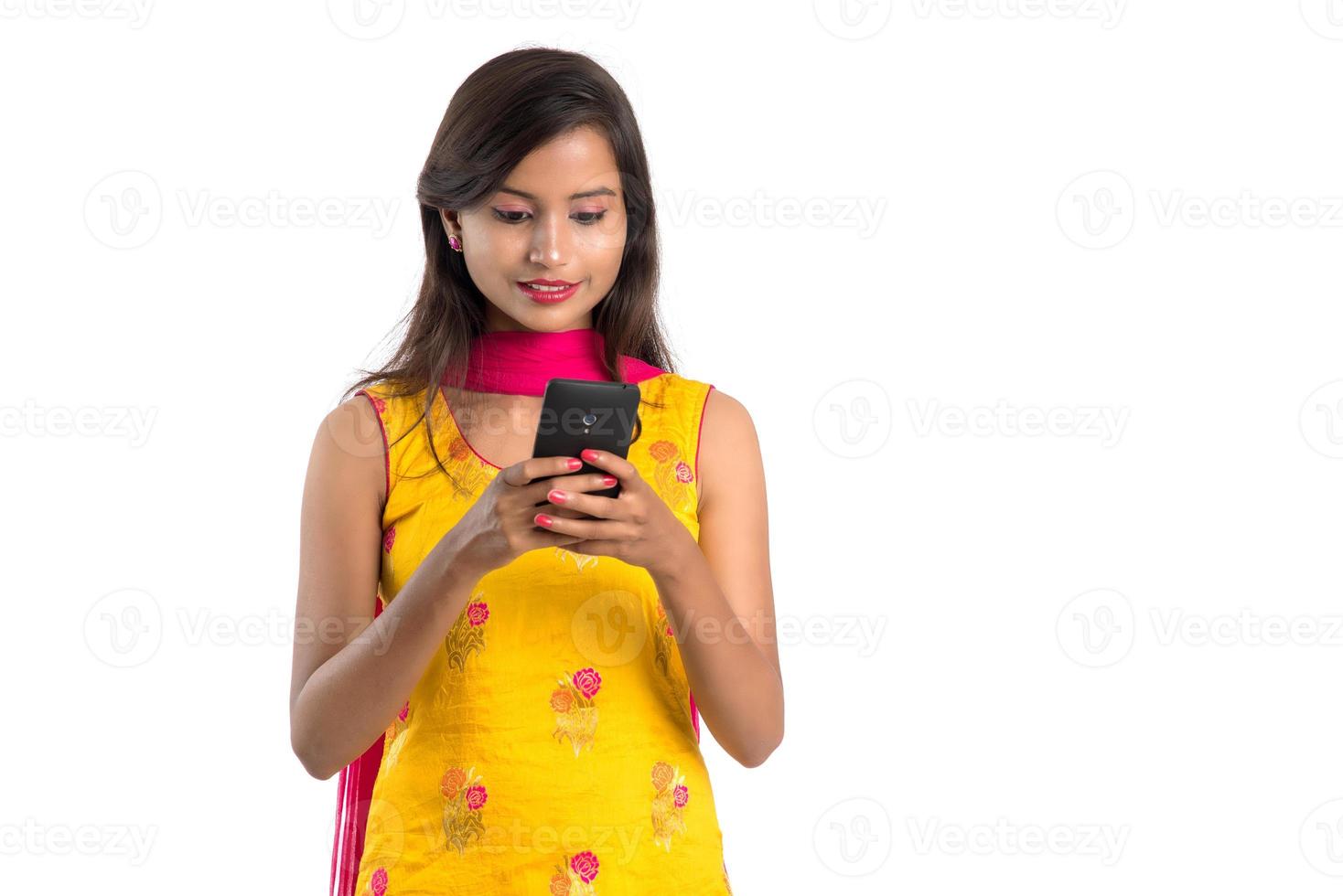 Young Indian girl using a mobile phone or smartphone isolated on a white background photo