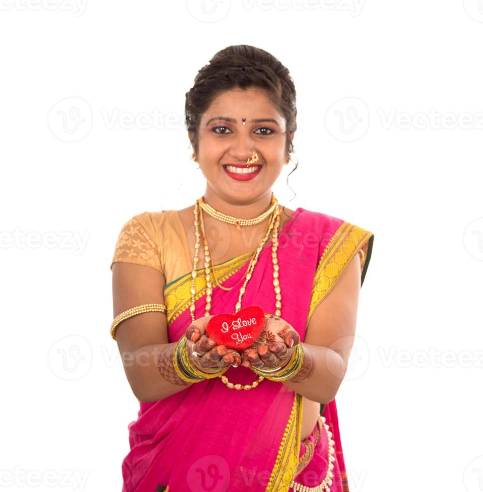 Traditional Beautiful Indian young girl in saree posing with Heart on white background photo