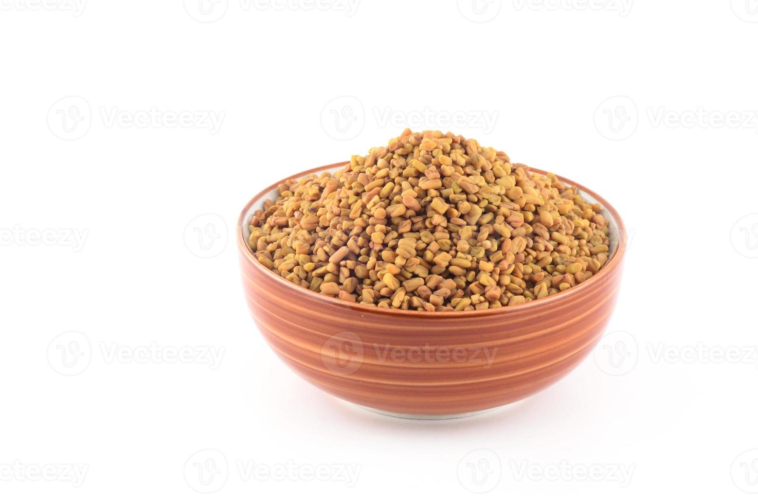 Fenugreek seeds in bowl isolated on white background photo