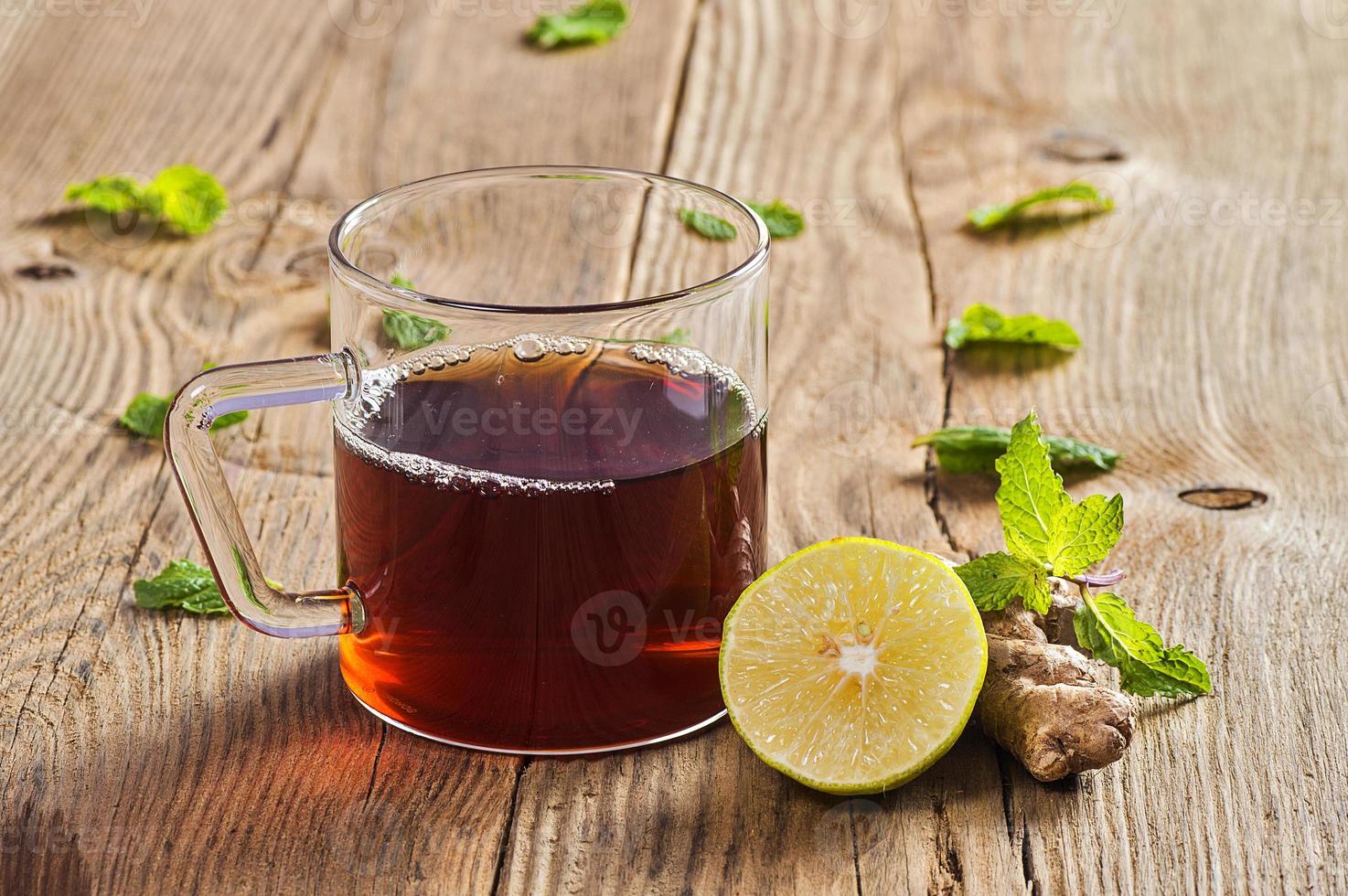Taza de té con jengibre, limón y menta en la mesa de madera foto