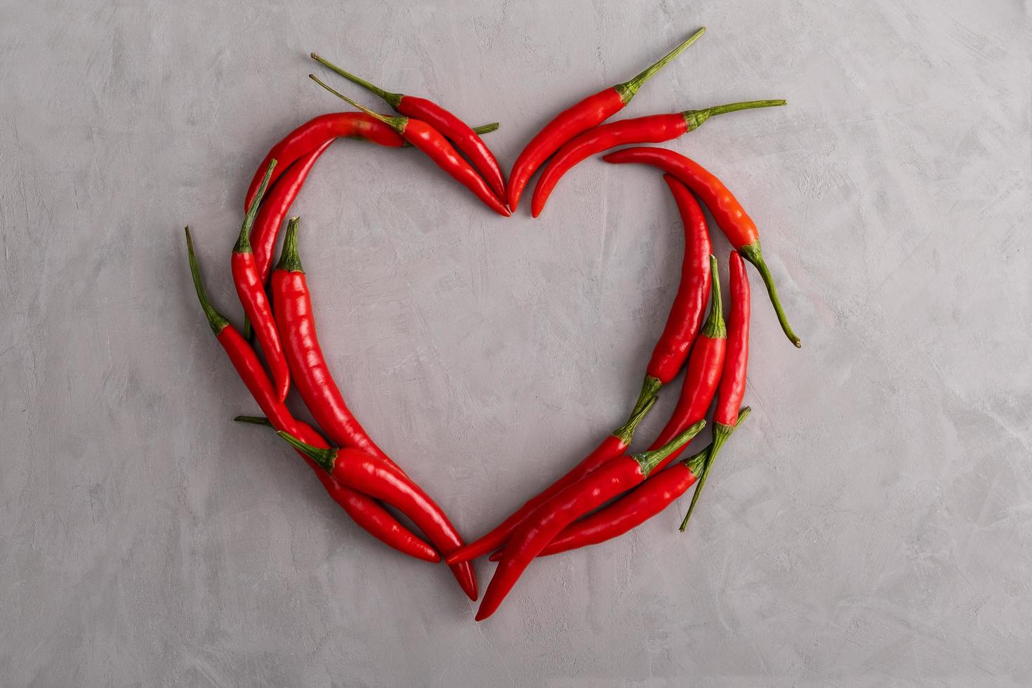 Contour in shape of heart is lined with pods of red hot peppers photo