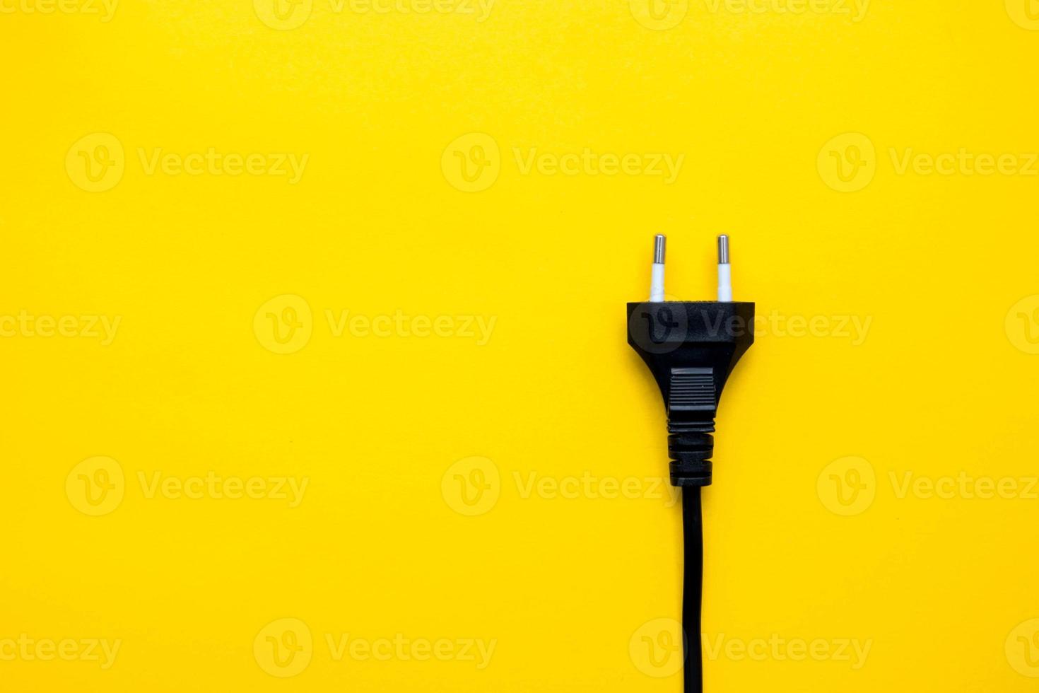 Conector de enchufe eléctrico negro sobre fondo amarillo. vista superior. copiar, espacio vacío para texto foto