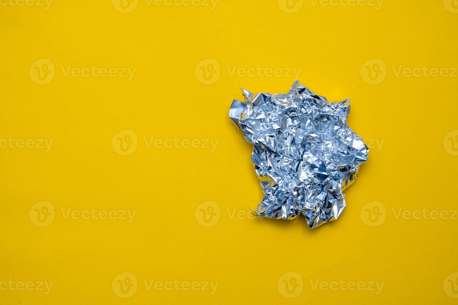 Silver foil on yellow background. Top view. Copy, empty space for text photo