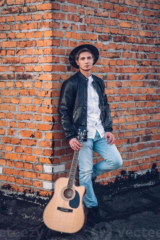 Man with a guitar on the background of a brick wall photo