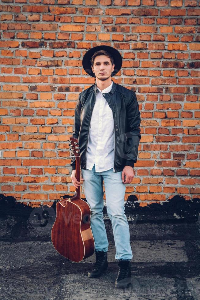 Man with a guitar on the background of a brick wall photo
