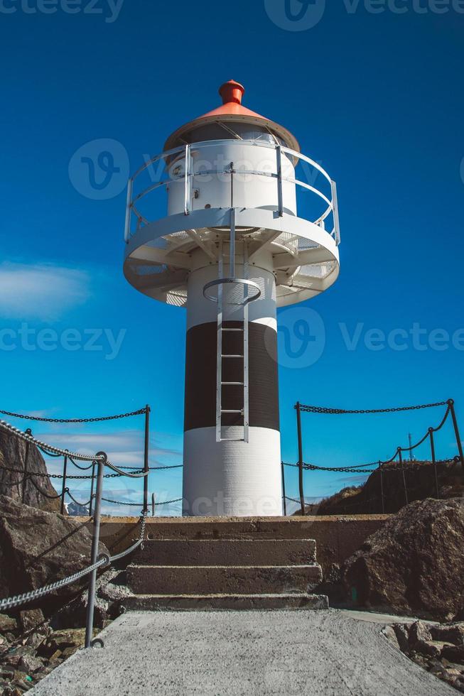 Lighthouse on the pier on the background of the mountains and the blue sky on the Lofoten Islands. Place for text or advertising photo