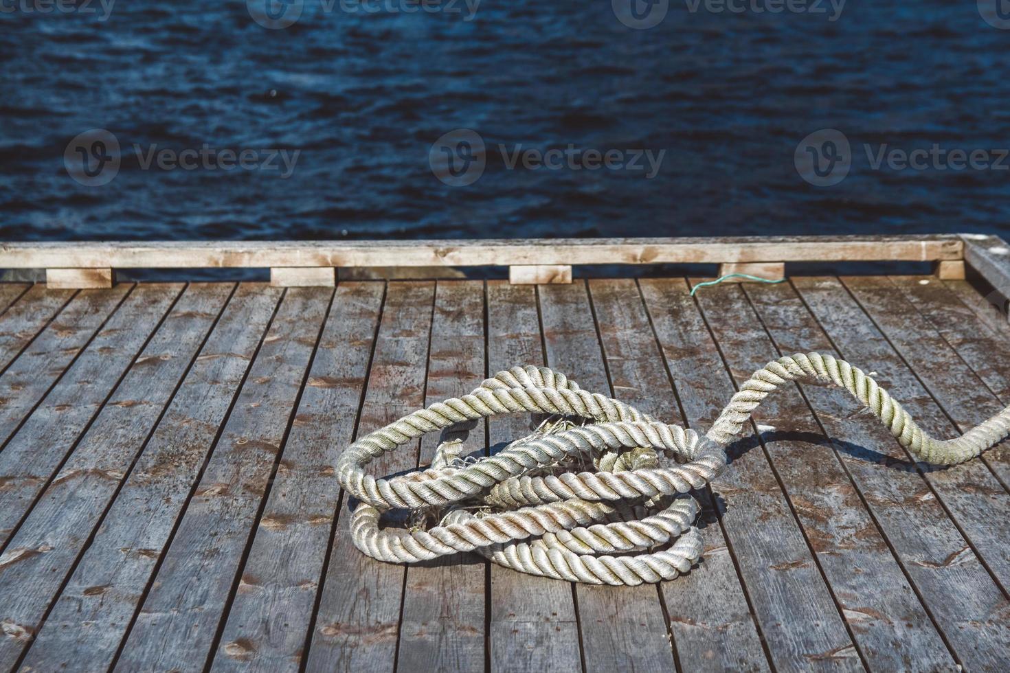 Worn out thick mooring rope on wooden pier. Can use as banner. Place for text or advertising photo