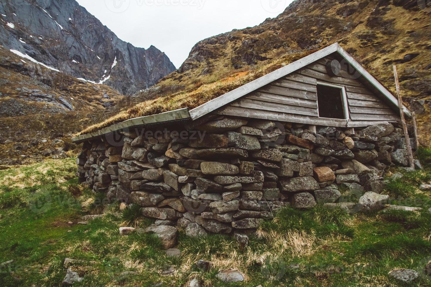 Antigua casa de piedra y madera cubierta de musgo en el fondo de las montañas. lugar para texto o publicidad foto