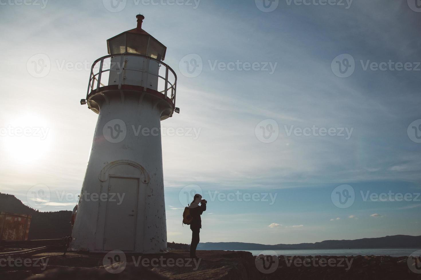 Silhouette of man taking photo on lighthouse background and dramatic sky. Place for text or advertising