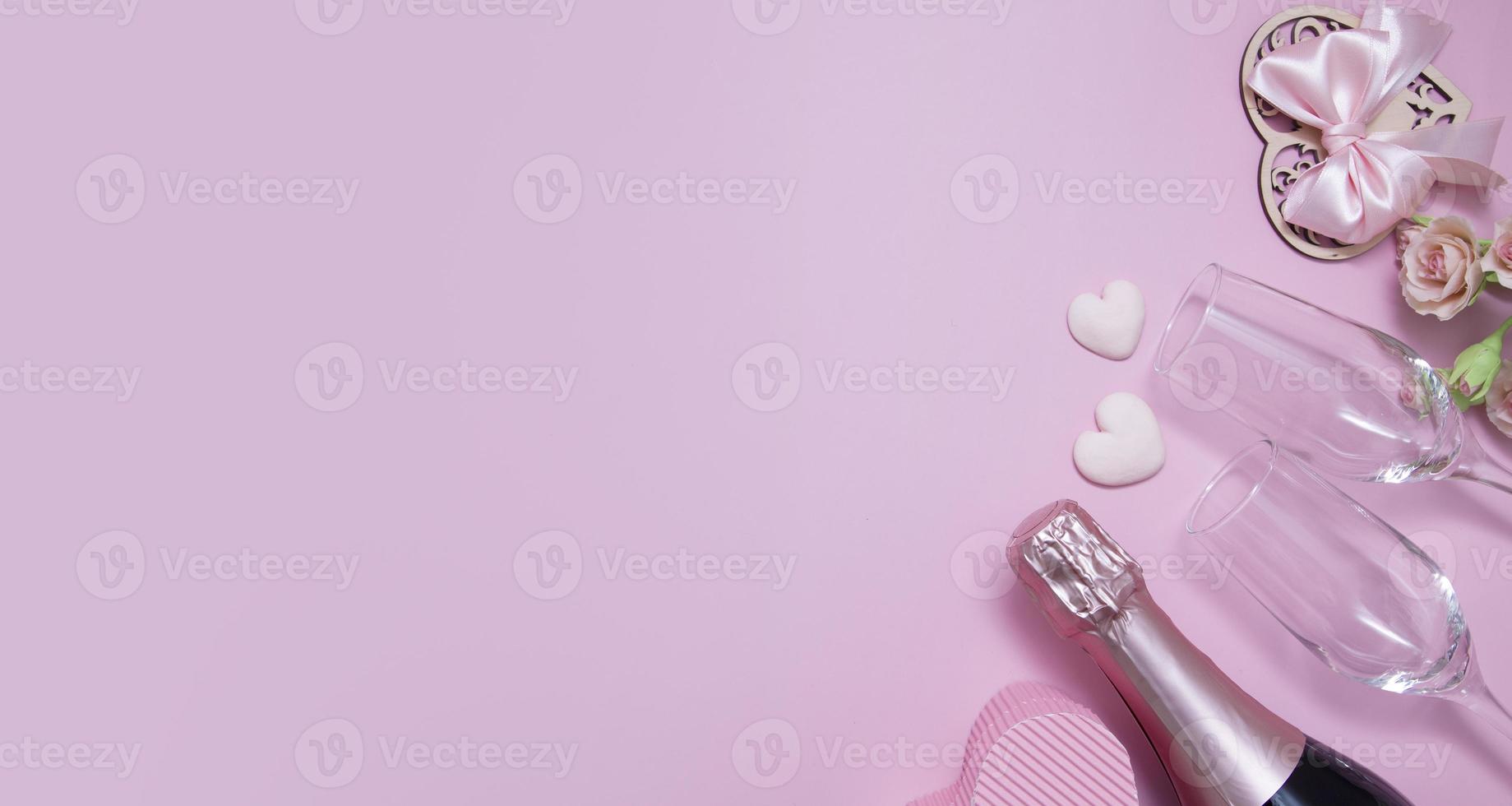 Top view two glasses, champagne, flowers on a pink background with copy space valentine's day date concept photo