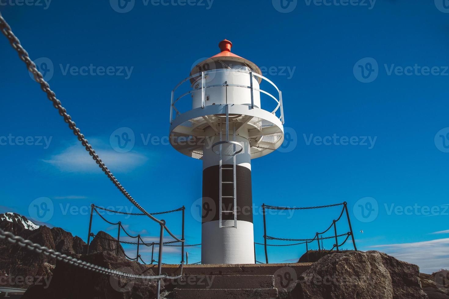 Lighthouse on the pier on the background of the mountains and the blue sky on the Lofoten Islands. Place for text or advertising photo