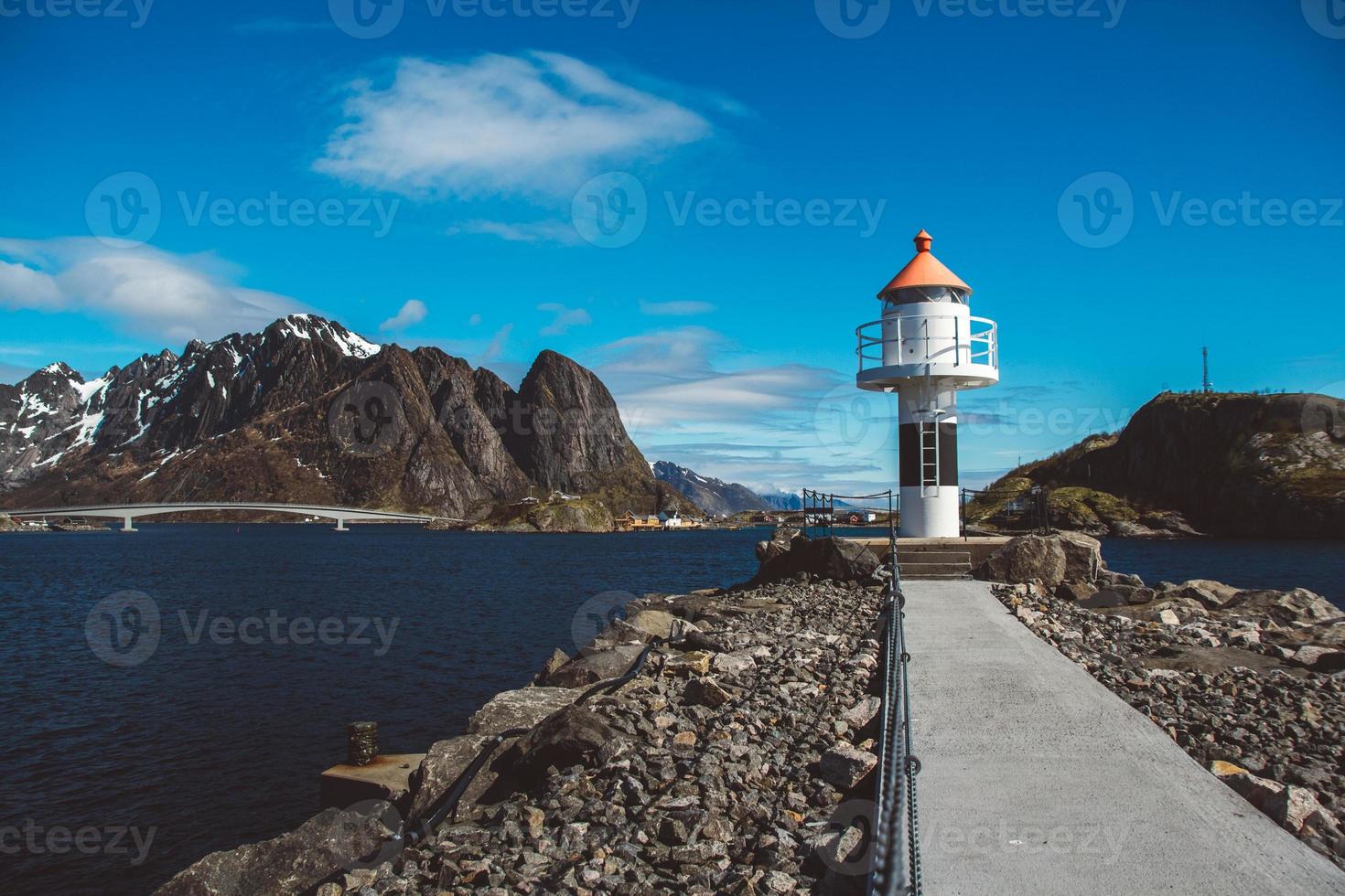 faro en el muelle en el fondo de las montañas y el cielo azul en las islas lofoten. lugar para texto o publicidad foto