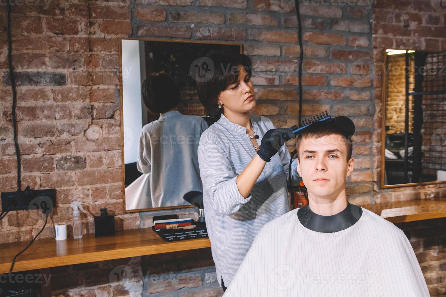 Peluquería hermosa mujer haciendo corte de pelo a hombre joven en peluquería. concepto de publicidad y peluquería. foto