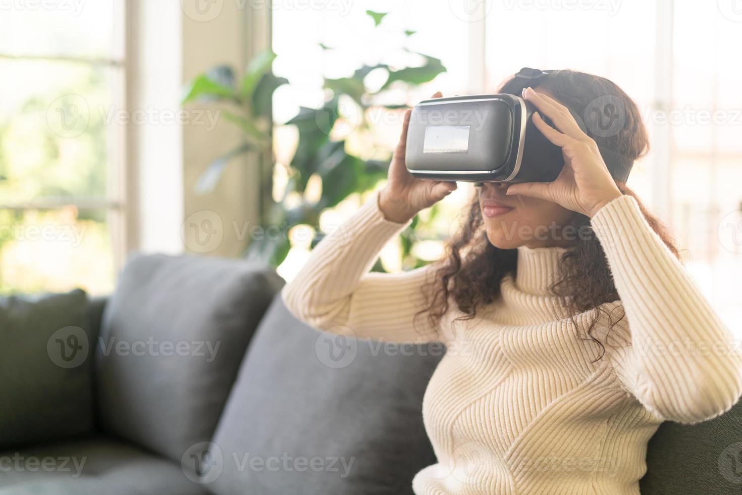 Mujer latina con un casco de realidad virtual en el sofá foto