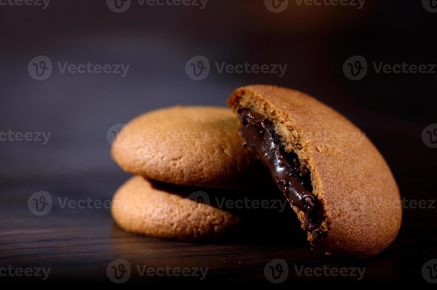 Biscuits filled with chocolate cream. Chocolate cream cookies. brown chocolate biscuits with cream filling on black background. photo