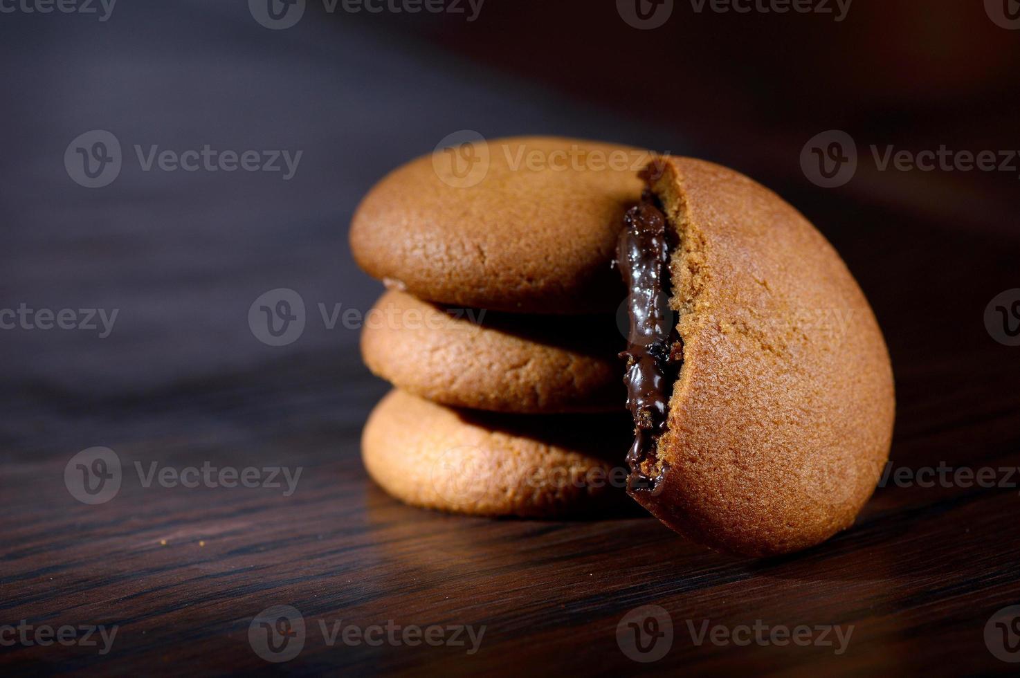 Biscuits filled with chocolate cream. Chocolate cream cookies. brown chocolate biscuits with cream filling on black background. photo