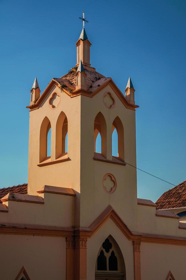Small church facade and belfry with sunlight on one side and shadow on the other, at sunset in Sao Manuel. A cute little town in the countryside of Sao Paulo State. Southeast Brazil. photo