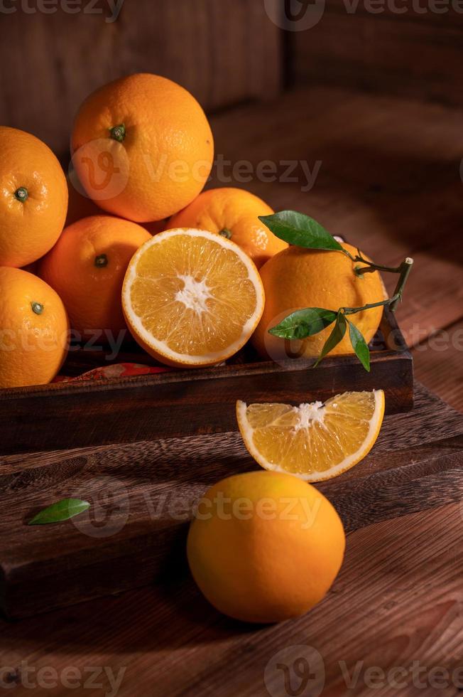 bajo la luz tenue, las naranjas en el plato están sobre la mesa de madera, como pinturas al óleo foto