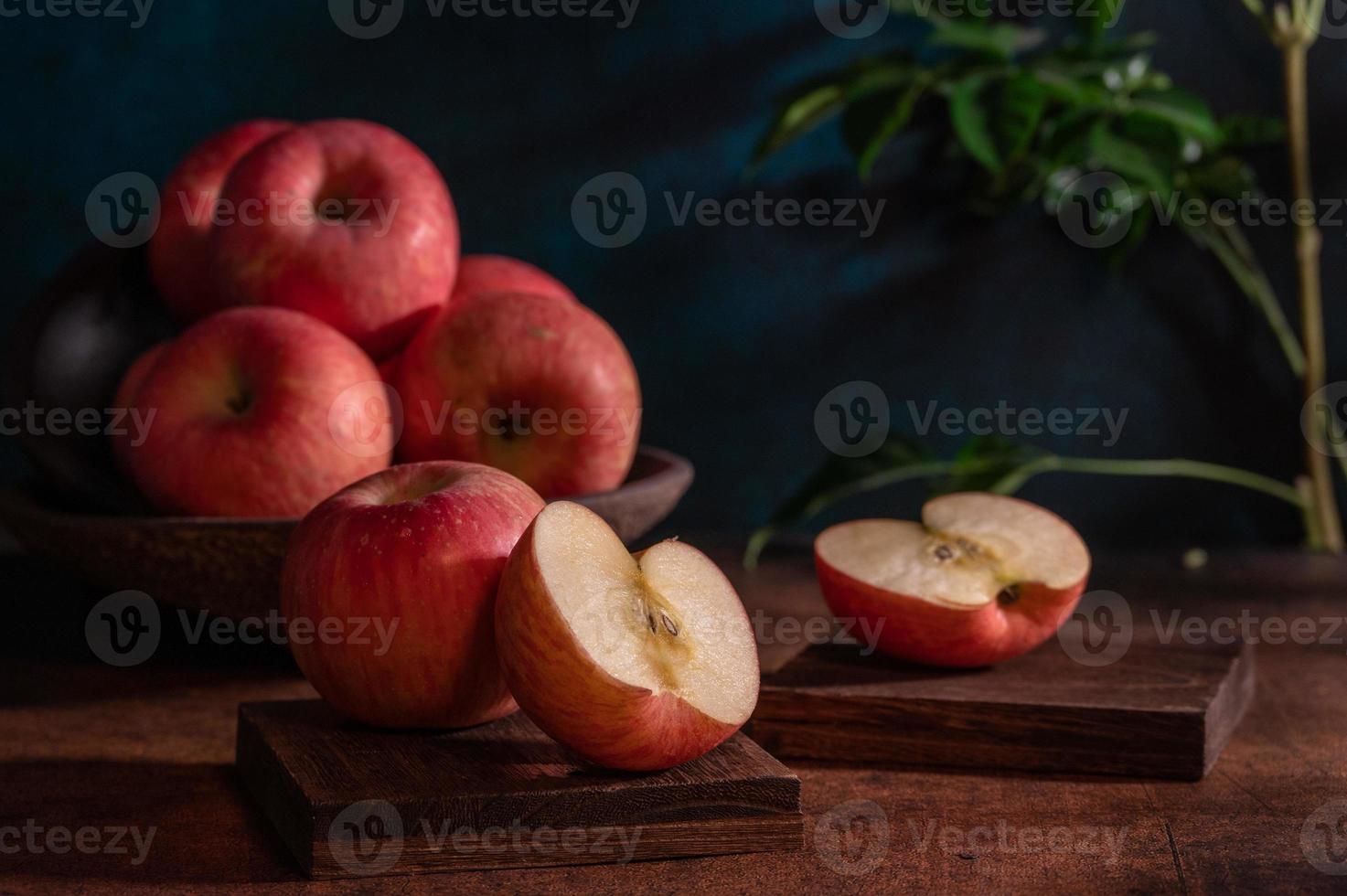 las manzanas en el plato parecen pinturas al óleo bajo la luz tenue de la mesa de madera foto