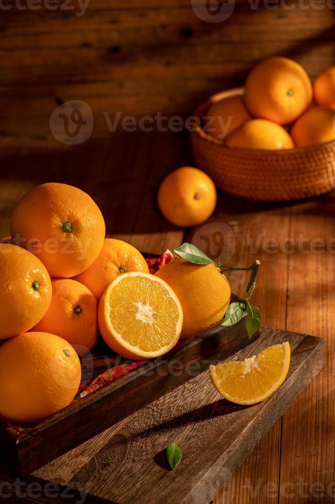 bajo la luz tenue, las naranjas en el plato están sobre la mesa de madera, como pinturas al óleo foto